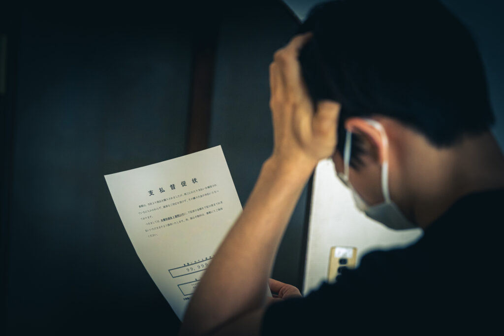 届いた書類を見て頭を抱える男性