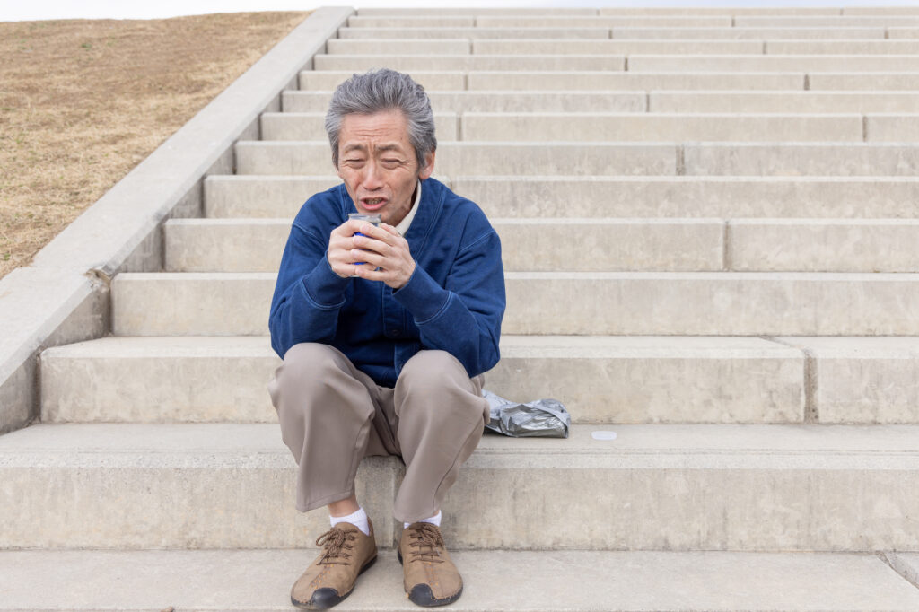 階段に座って缶を手に考え込む男性