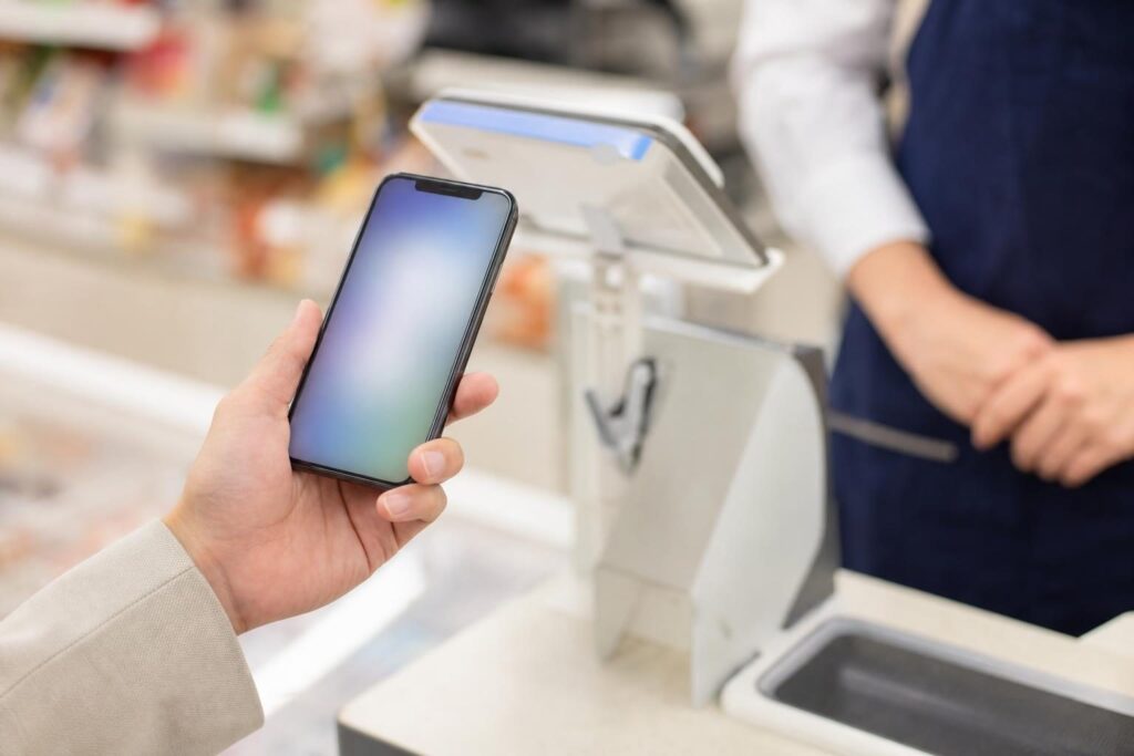 コンビニのレジでスマートフォンをかざす手元
