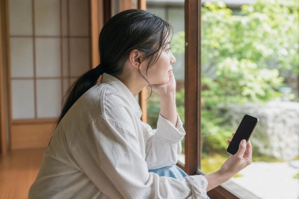 スマートフォンを手に考え込む人物