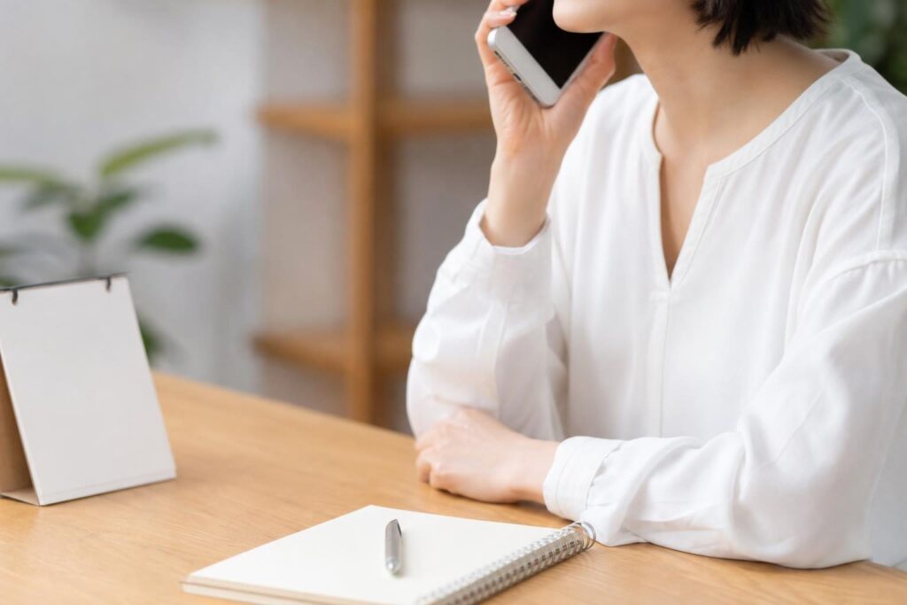 カレンダーを見ながら電話をかけようとする手元