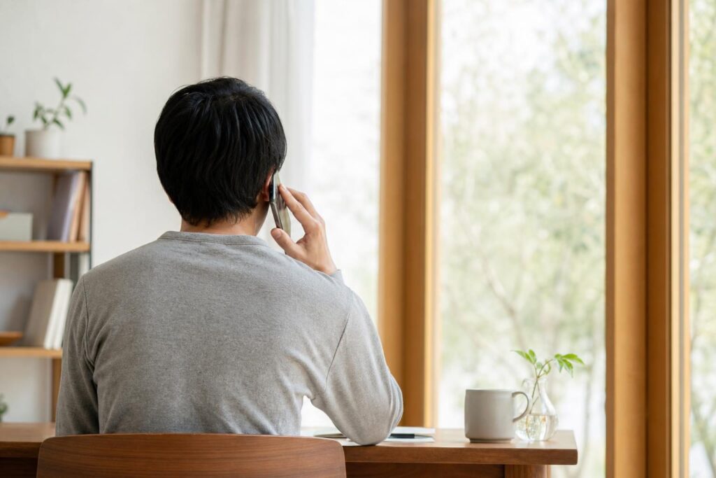 窓辺で電話をかける後ろ姿の人物