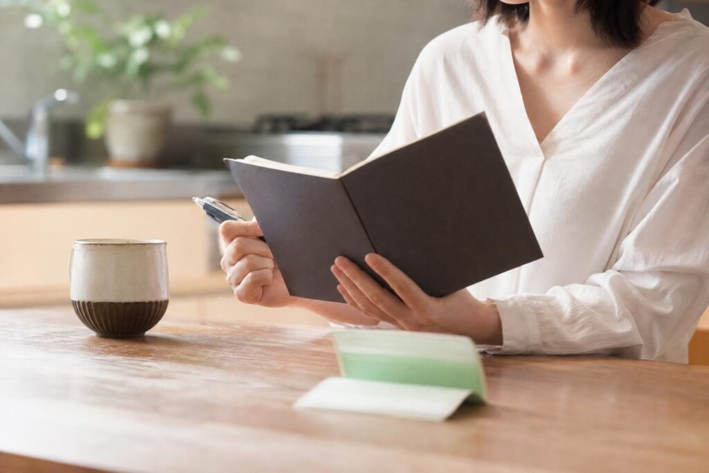 通帳と家計簿を並べて支払い予定を確認する手元