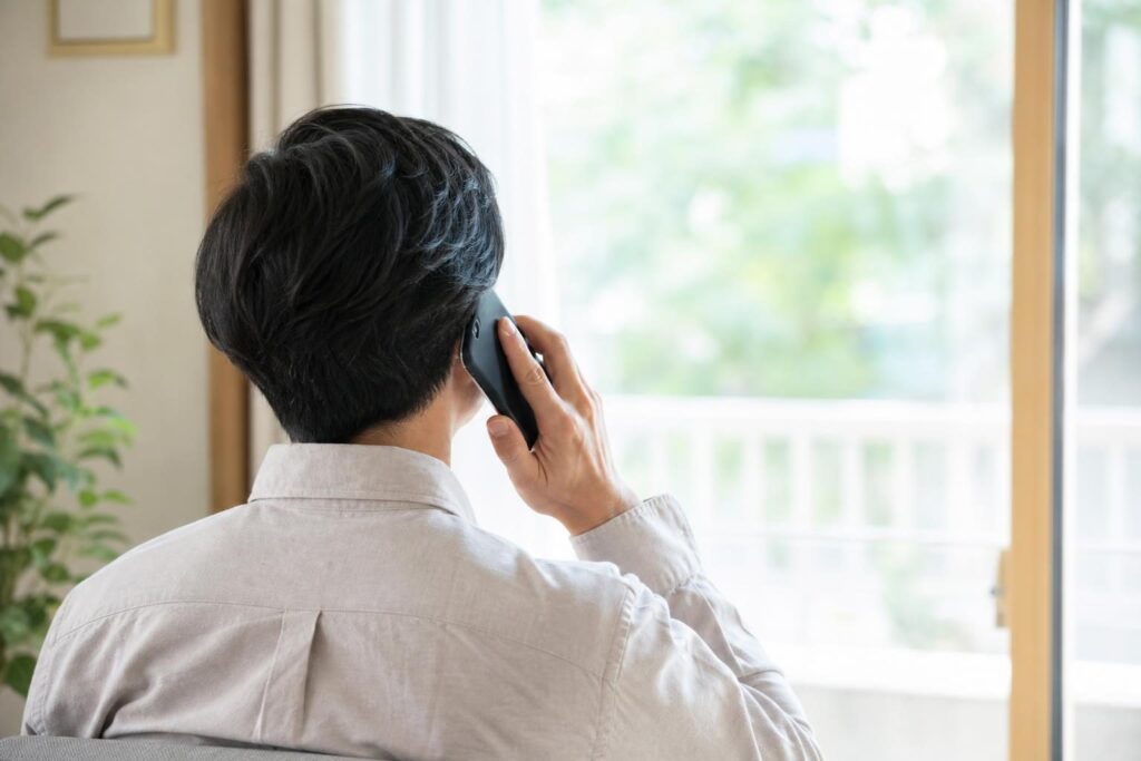相談窓口に電話をかける後ろ姿