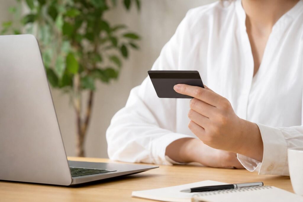 クレジットカードを手にして考える人の手元