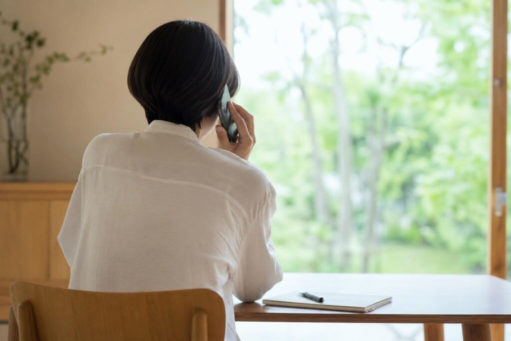 電話で相談する人の後ろ姿