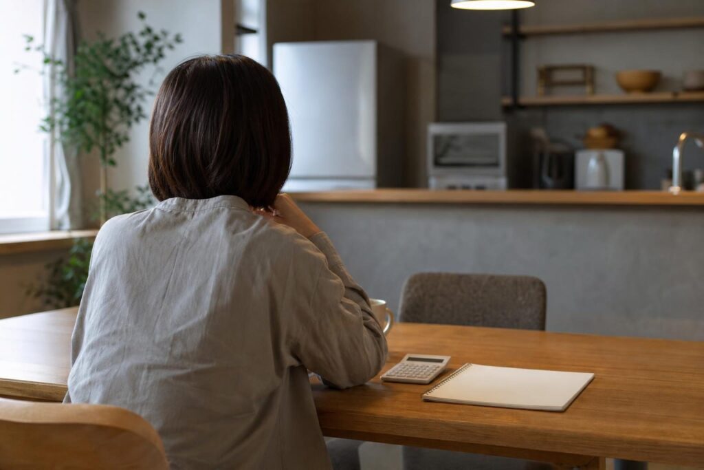 電卓を前に家計を確認する後ろ姿の人物