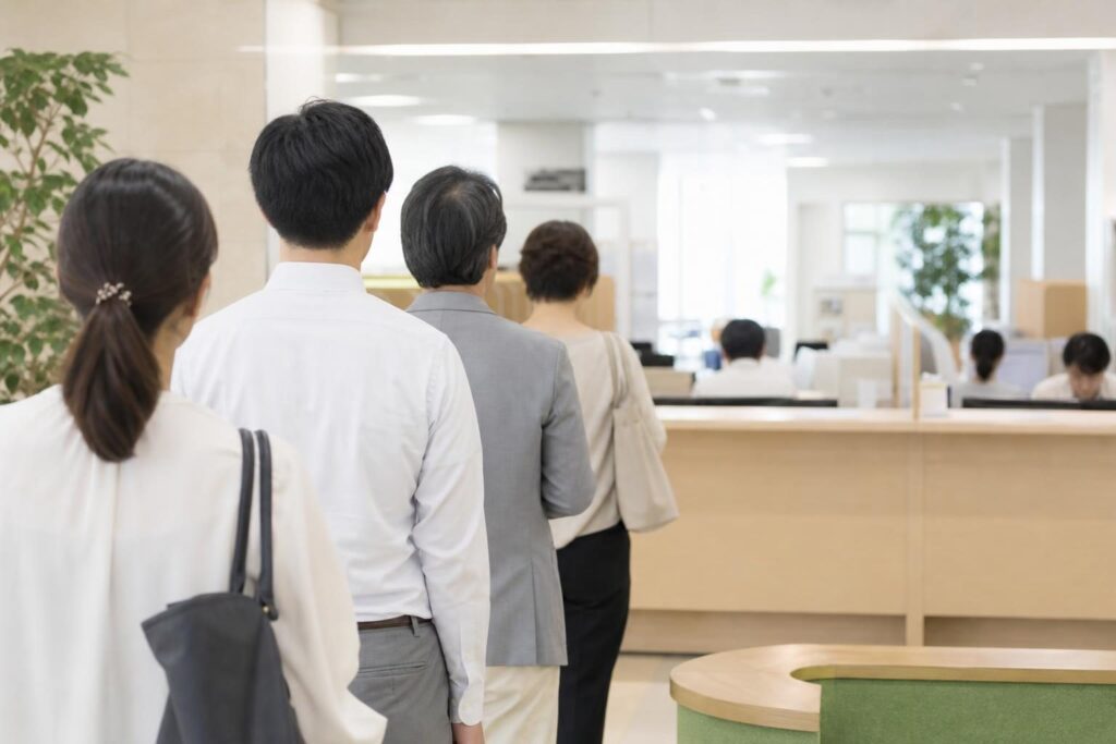 市役所の窓口に並ぶ人々の後ろ姿