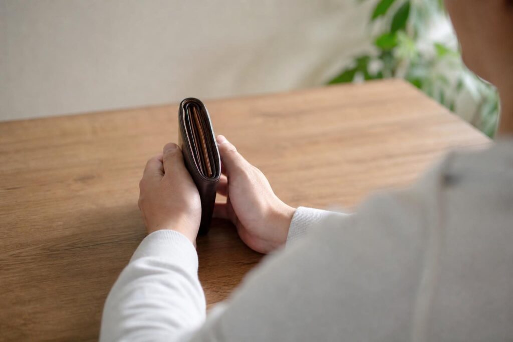 テーブルの上で財布を手にする手元