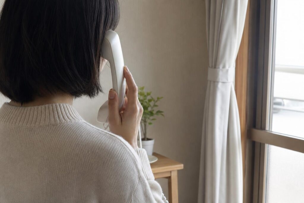 電話の受話器を持つ手元、慎重な雰囲気