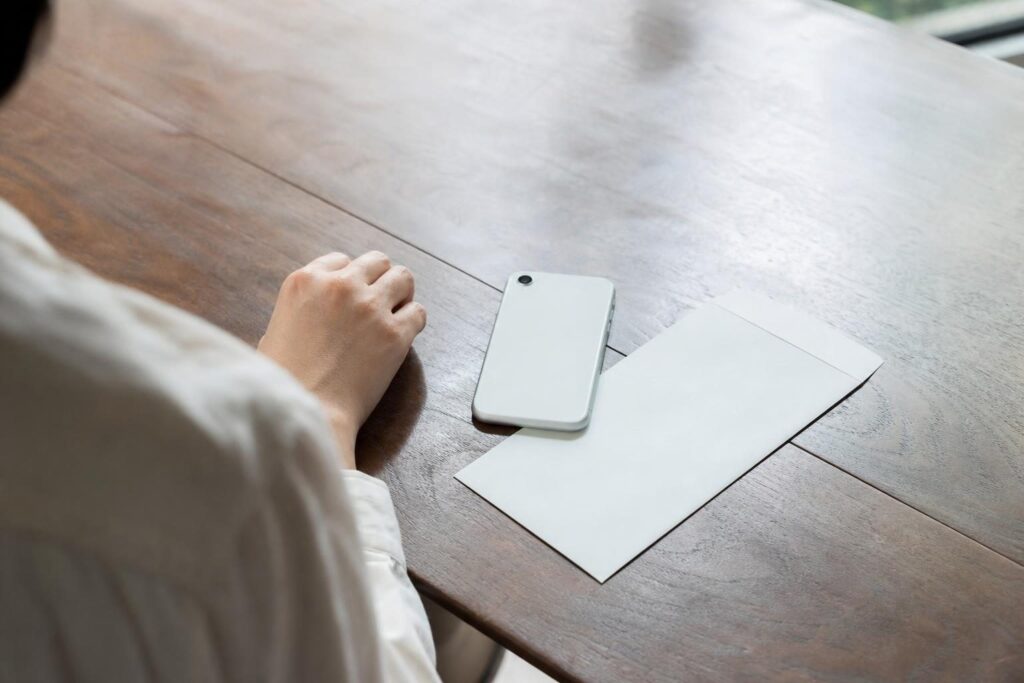 伏せたスマートフォンと封筒のそばの手元