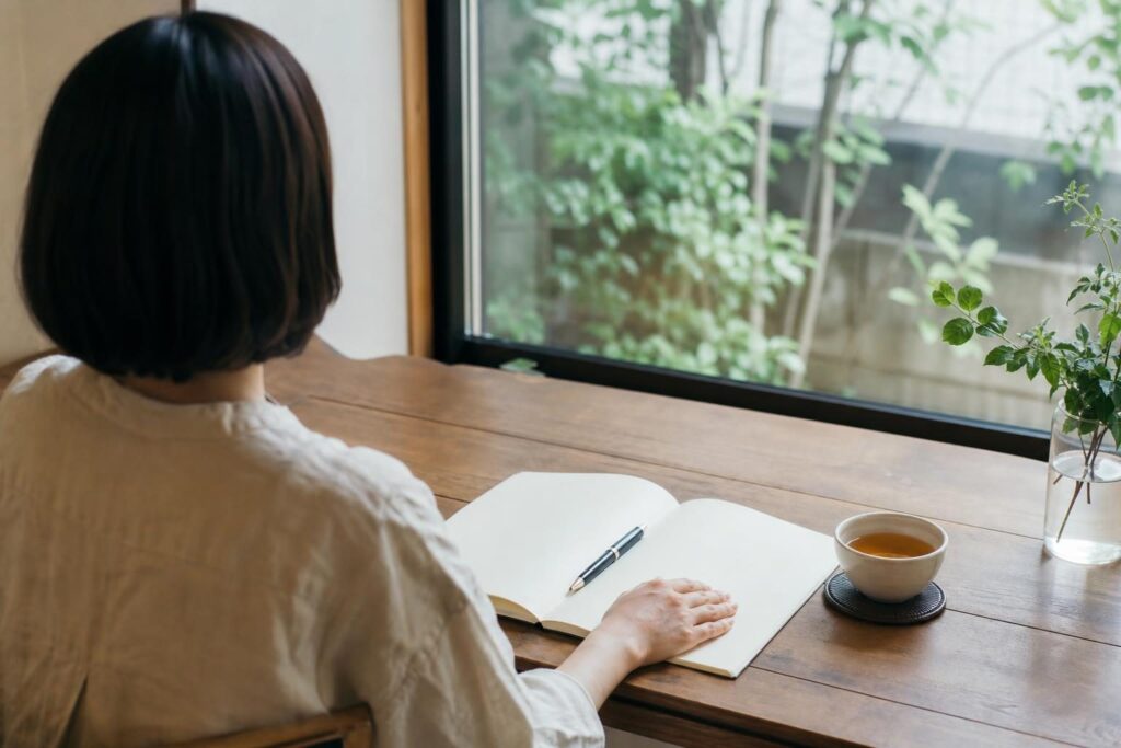 机でノートを前に考える人の後ろ姿