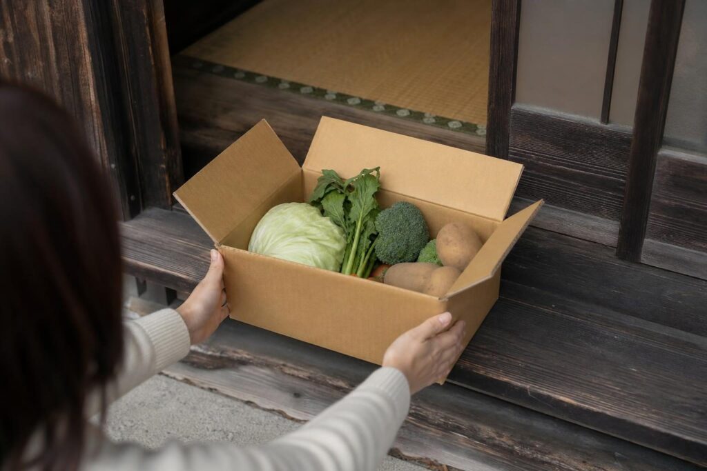 玄関先で届いた箱を受け取る手元